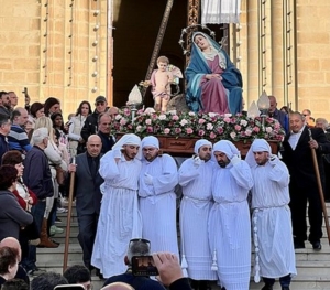 Five men in hooded white religious garb carrying a statue in a procession